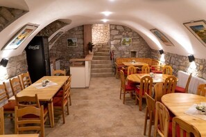 Un restaurant avec des tables et des chaises en bois, des murs en pierre et un escalier menant à un étage supérieur.
