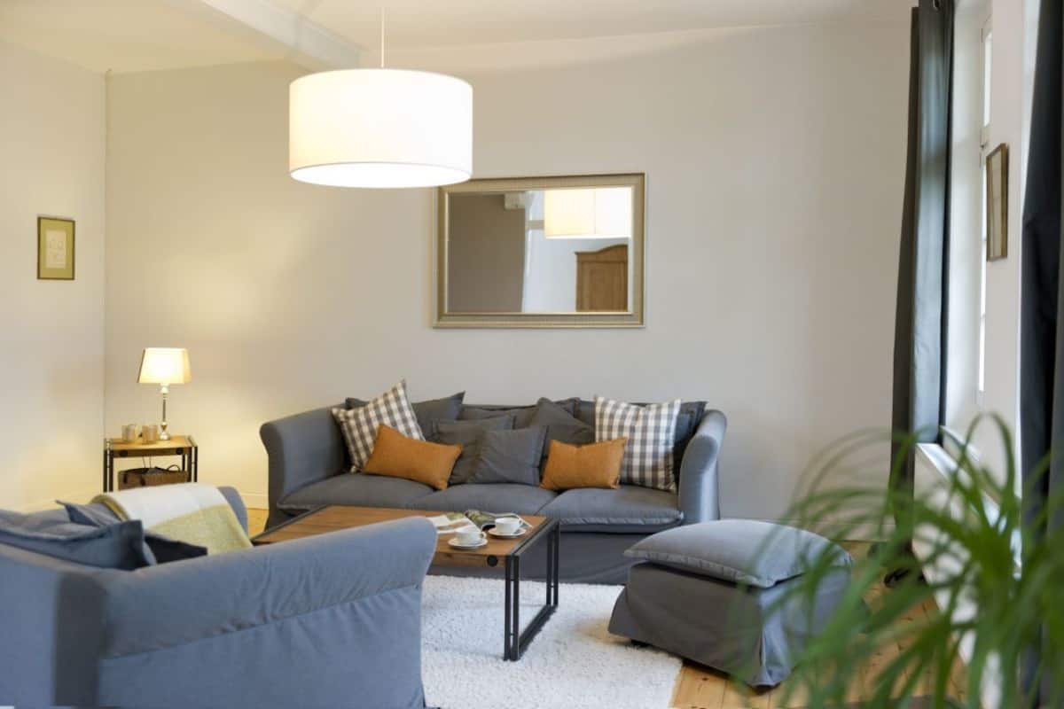 Uma sala de estar moderna com um sofá cinza, uma mesa de centro e uma luminária.