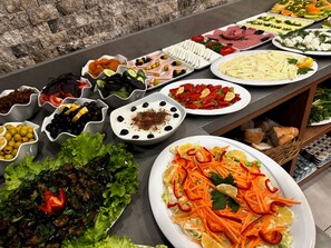 Un buffet proposant une variété de plats, notamment des salades, des viandes et des fromages.