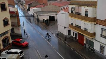 Una vista di strada con edifici, auto parcheggiate e un ciclista.