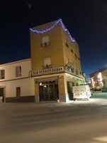 Un edificio con un letrero que dice "BAR PENSION RUDA" y una camioneta estacionada frente a él.
