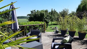 Een terras buiten met rieten meubilair en plantenpotten.