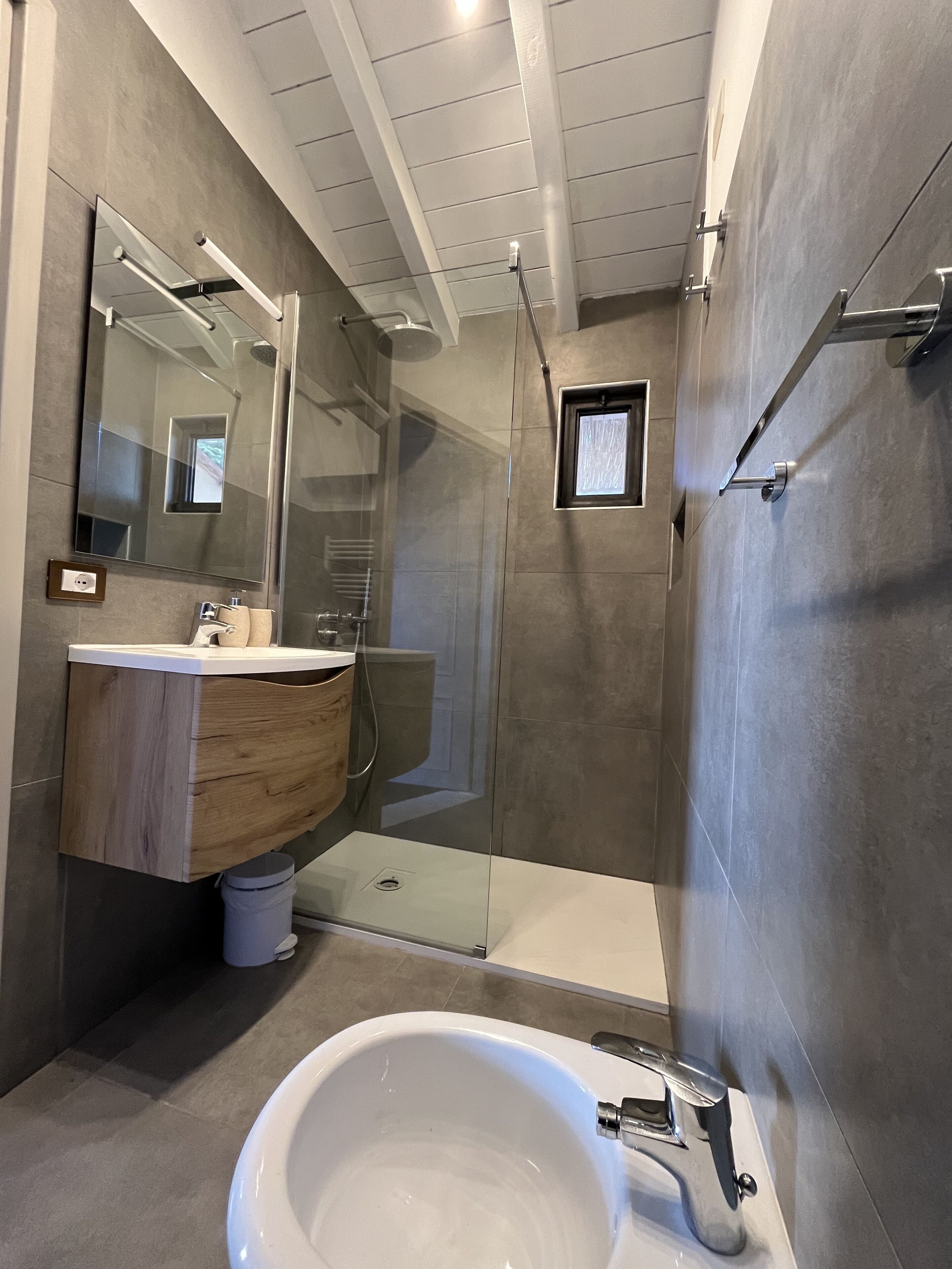A modern bathroom with a large bathtub, a glass-enclosed shower, and a wooden vanity.