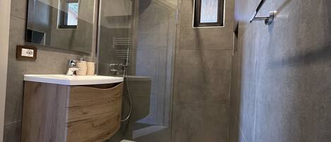 A modern bathroom with a large bathtub, a glass-enclosed shower, and a wooden vanity.