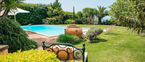 Una piscina al aire libre, sombrillas, sillones reclinables de piscina