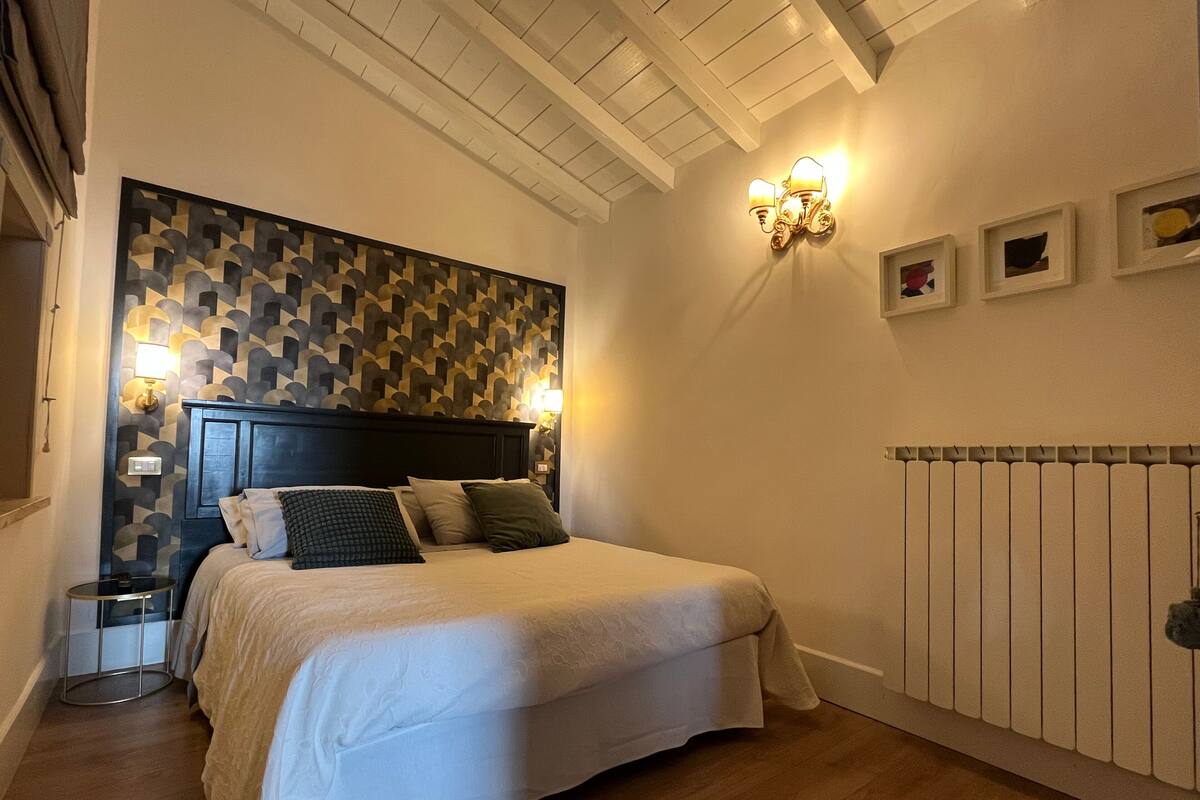 Un dormitorio con cama, pared estampada, aplique de pared y radiador.