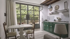 Een eethoek met een tafel en stoelen, een keuken met groene kastjes en een groot raam met gordijnen.