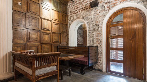 Una habitación con un banco de madera, una mesita y un carrito.