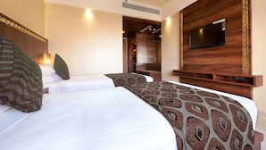 Una habitación de hotel con dos camas, un televisor montado en la pared y un cabecero de madera.