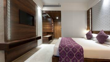 A modern hotel room with a large bed, a TV mounted on the wall, and a wooden accent wall.