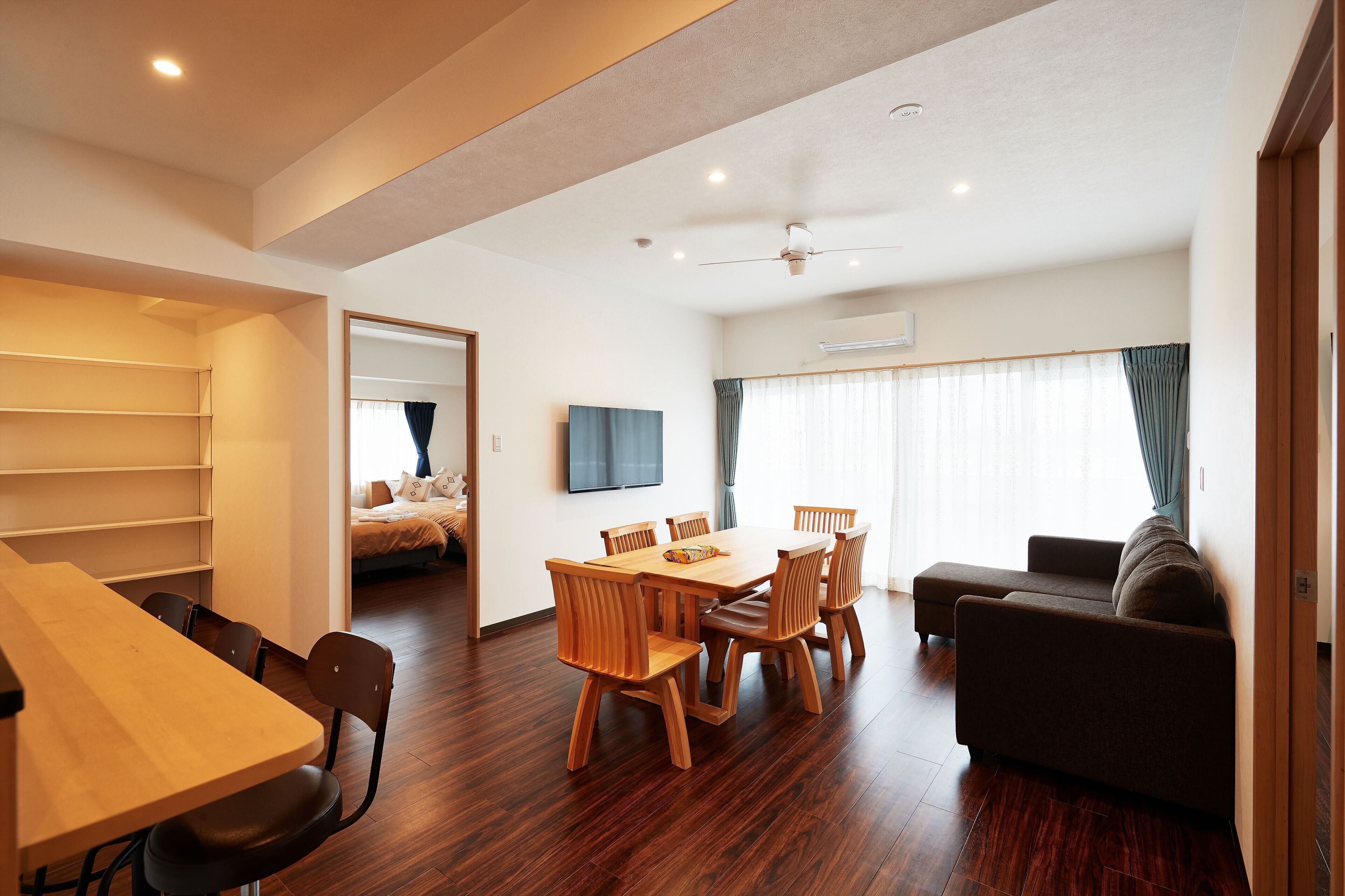A modern living room with a dining area, wooden furniture, and a flat-screen TV.