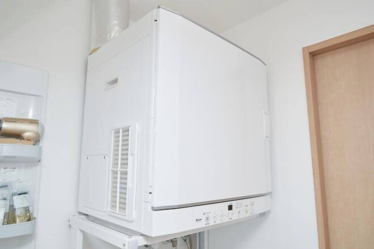Unidade de ar condicionado branca fixada na parede, com uma porta de madeira por perto.