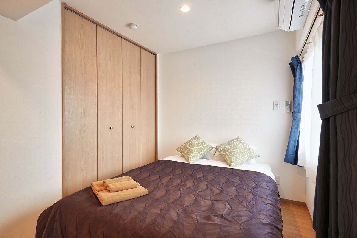 A bedroom with a bed, a wardrobe, and a window with curtains.