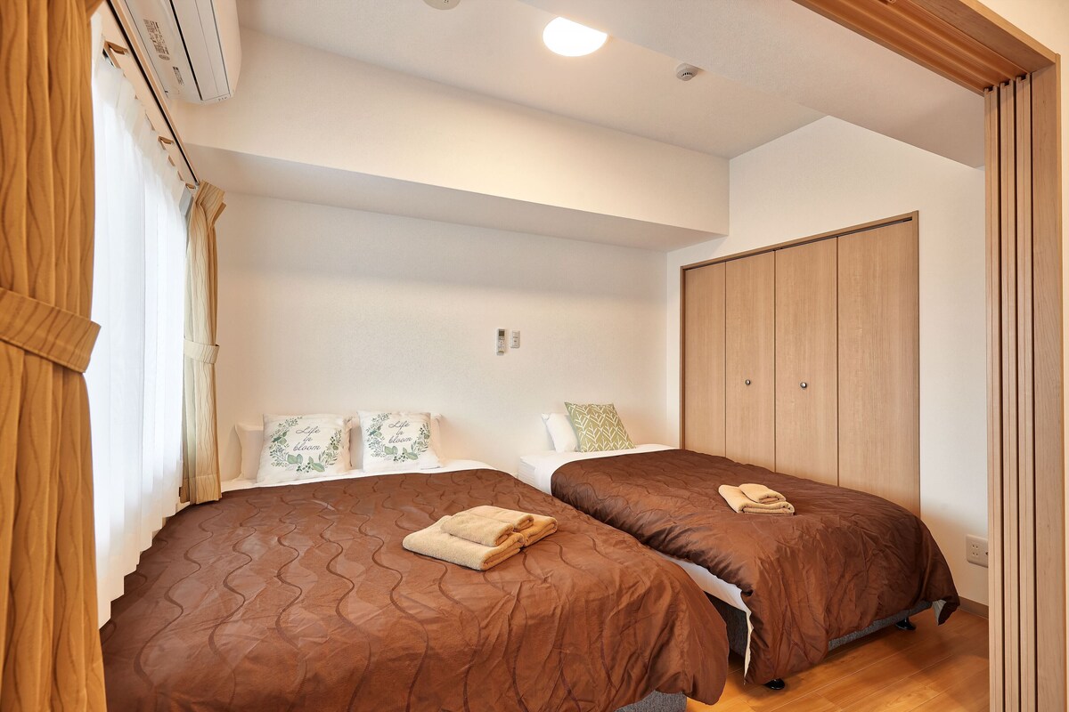 A bedroom with two beds, a wardrobe, and an air conditioning unit.