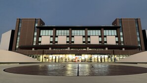 Un edificio moderno con una entrada amplia y una plaza circular frente a él.