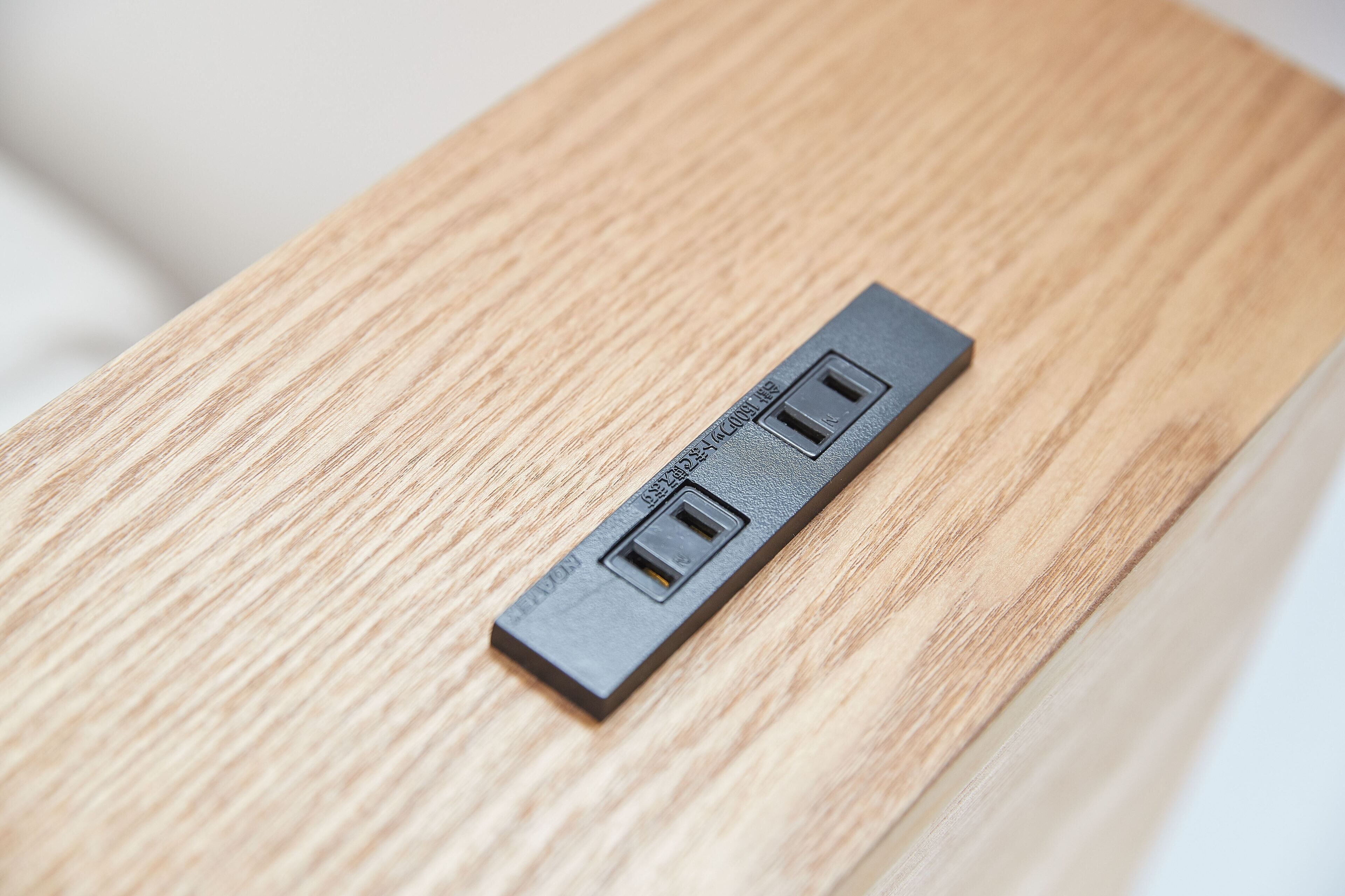 Un enchufe eléctrico negro sobre una superficie de madera.