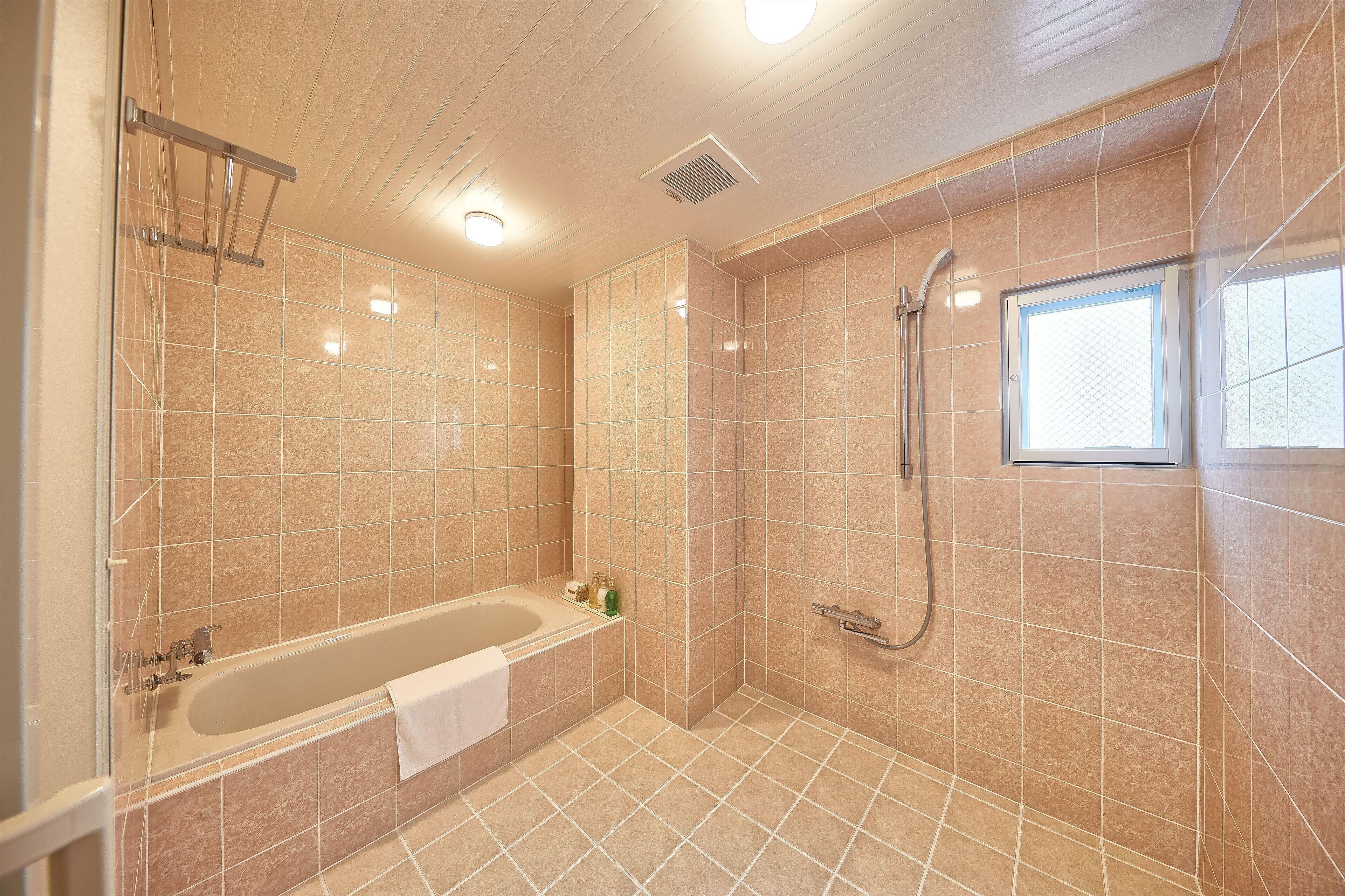 A modern bathroom with a bathtub, shower, and tiled walls.