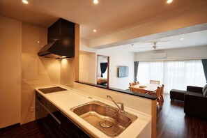 A modern kitchen with a built-in stove, sink, and overhead ventilation hood. - M's Stay Okinawa (Chatan)