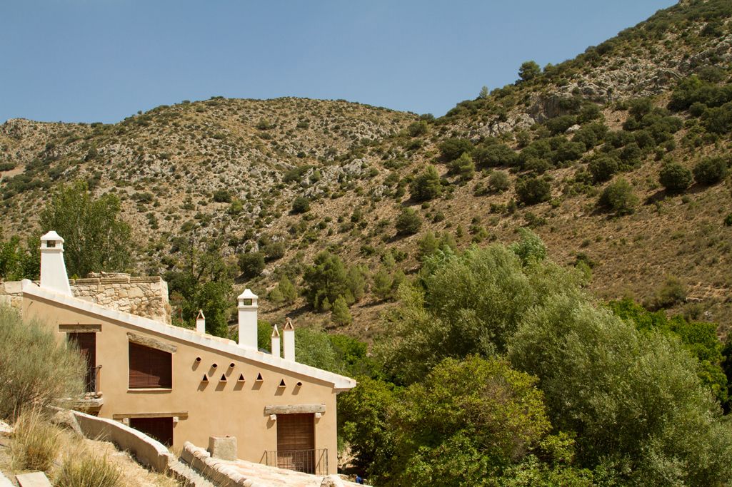 Un bâtiment traditionnel en pierre, doté d’un toit en pente, de plusieurs cheminées et d’une apparence rustique.