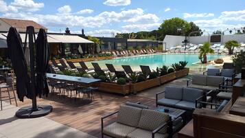 Een buitenzwembad, parasols bij het zwembad en ligstoelen