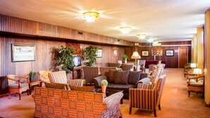 A spacious lobby with multiple seating areas, including patterned sofas and armchairs, and a reception desk in the background. - Elgro Hotel (Potchefstroom)