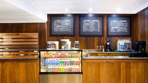 A modern kitchen area with wooden cabinets, a refrigerated beverage display, and a coffee machine. - Elgro Hotel (Potchefstroom)
