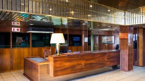 A reception desk with a wooden finish, a lamp, and a clock on the wall. - Elgro Hotel (Potchefstroom)