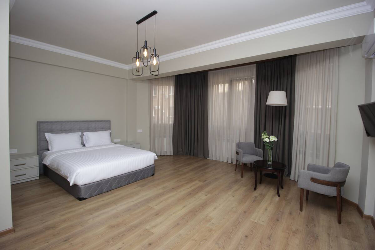 A modern hotel room with a large bed, a desk with a chair, and a TV.