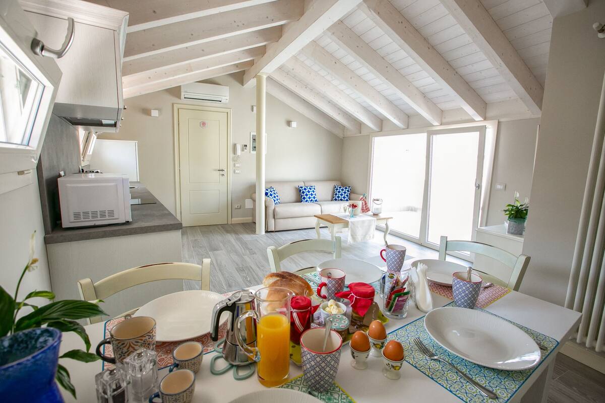 A bright kitchen with a dining area, featuring a breakfast setup with eggs, toast, and juice.