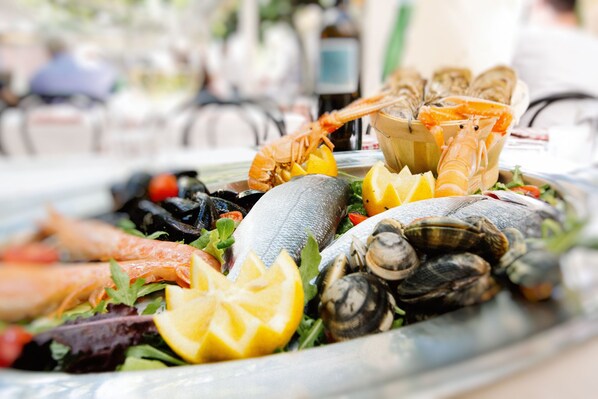 A seafood platter with various types of fish, shrimp, and mussels, garnished with lemon slices. - San Lorenzo Apartments (Sirmione)