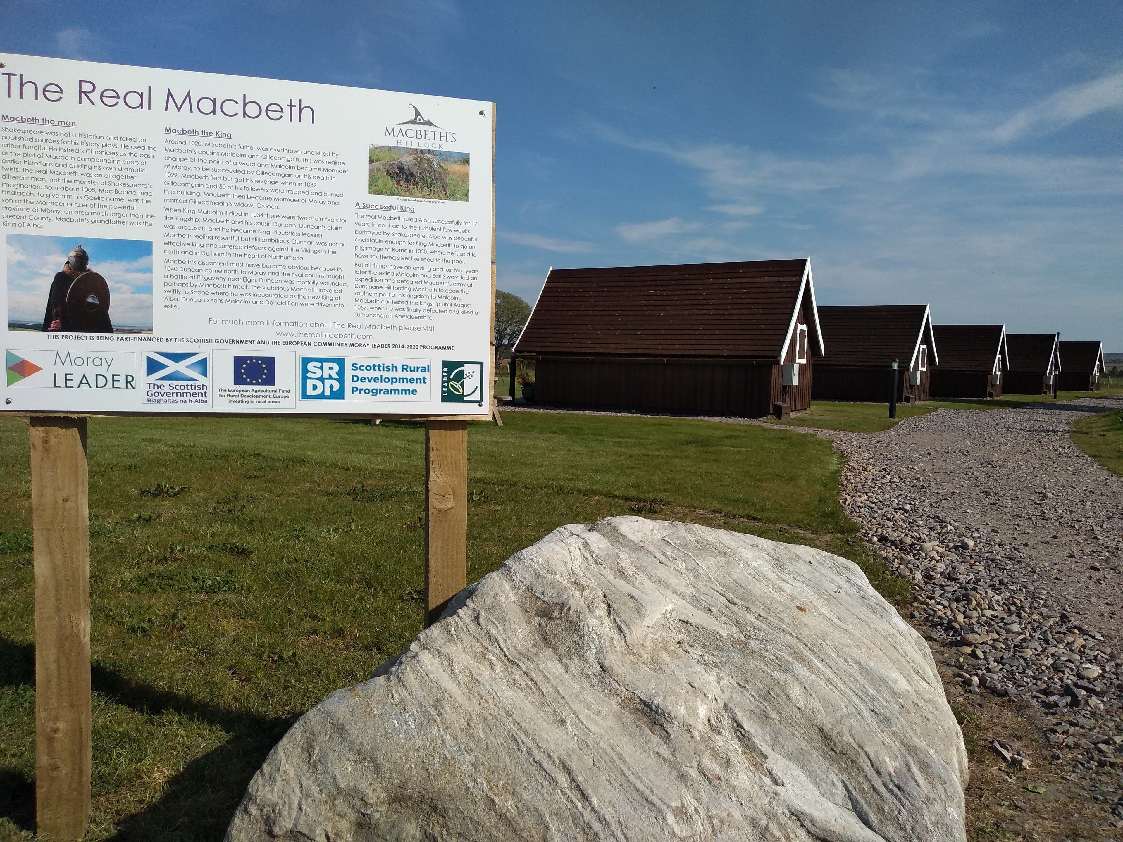 A signboard titled "The Real Macbeth" with historical information and logos of sponsors.