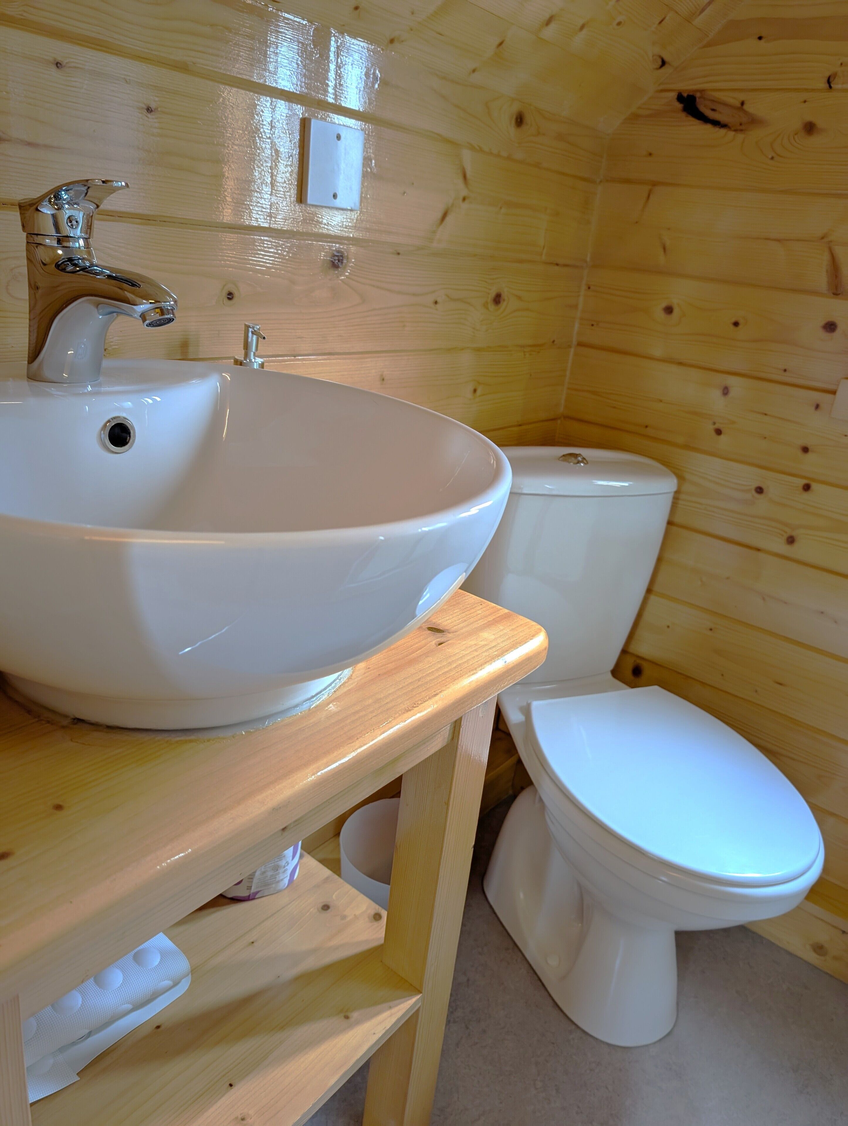 A wooden cabin bathroom with a white sink and toilet.