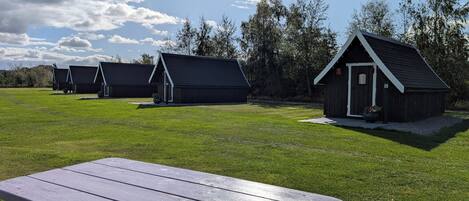 Une zone herbeuse avec des tables de pique-nique et plusieurs cabanes en bois.