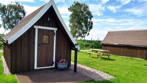 A small wooden cabin with a pitched roof, a door, and a window. - Macbeth's Hillock (Nairn)