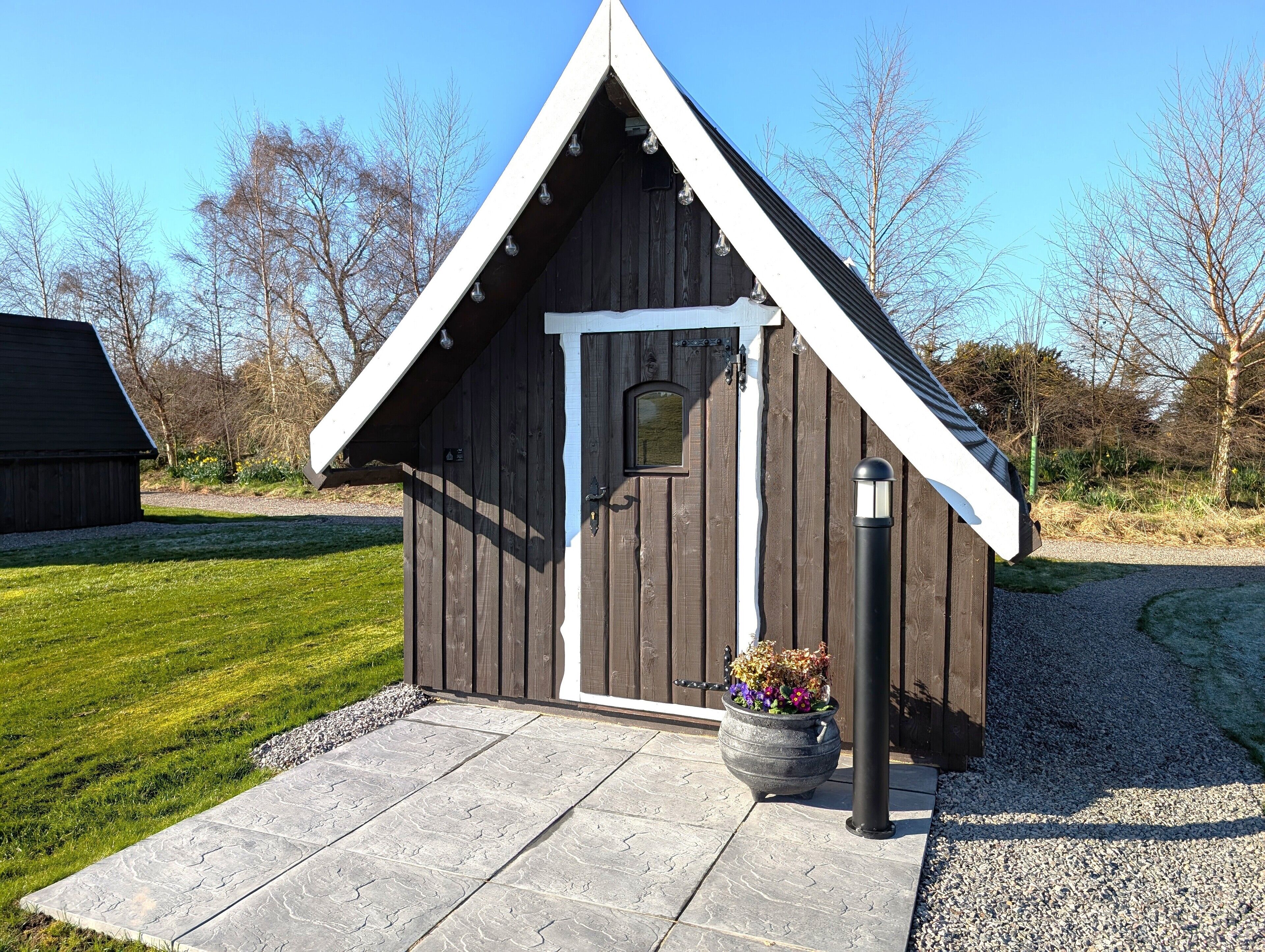 A small wooden cabin with a white door and a triangular roof.