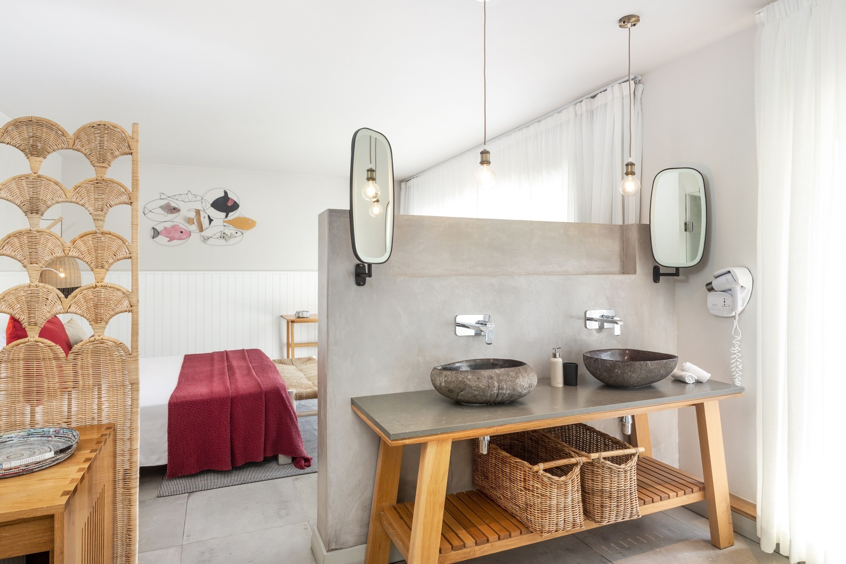 A modern bathroom with a wooden vanity, two mirrors, a stone sink, and wicker baskets.