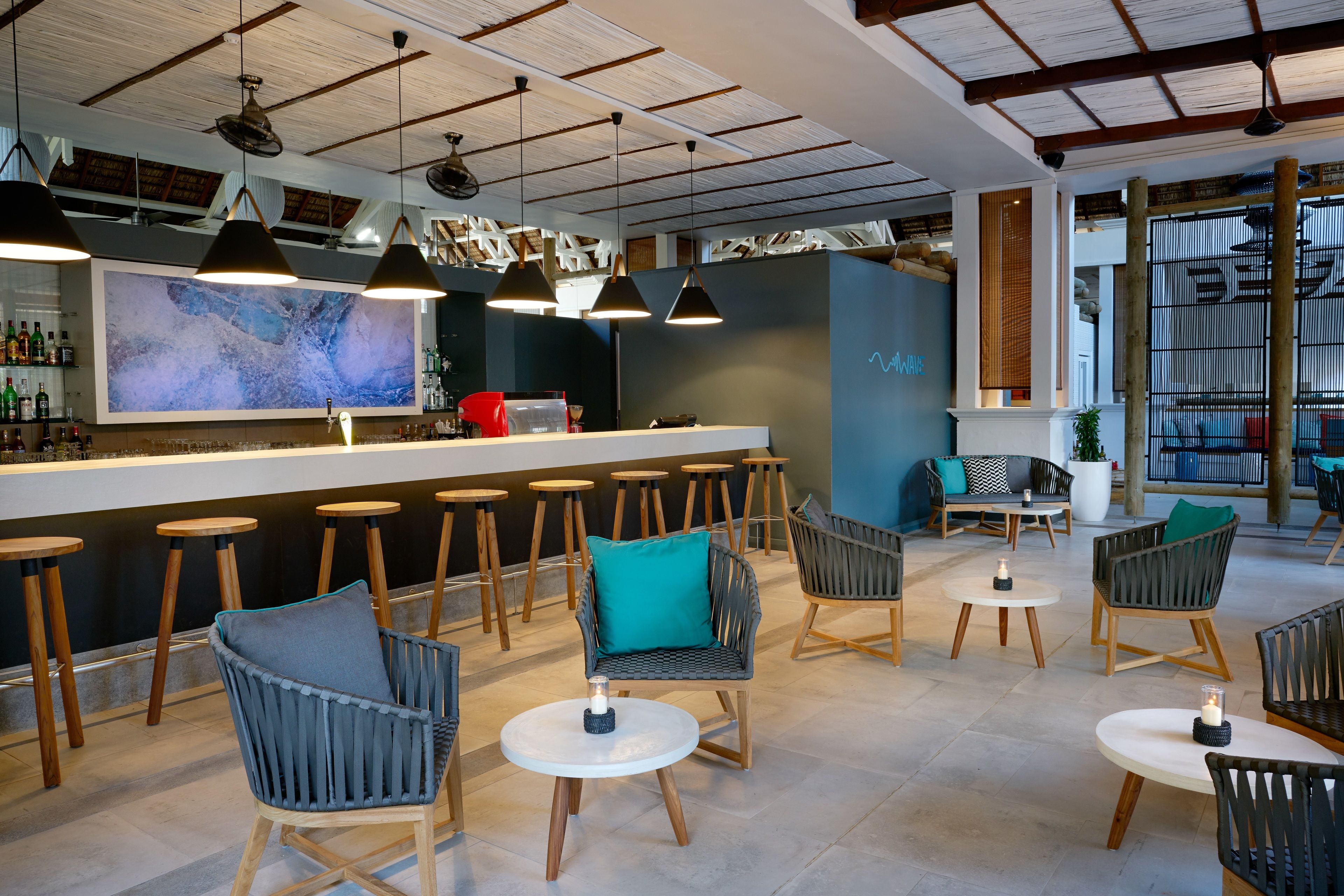 Uma área de bar moderna com taburetes altos, cadeiras estofadas e um amplo balcão.