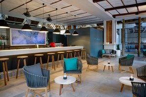 A modern bar area with high stools, cushioned chairs, and a large bar counter.