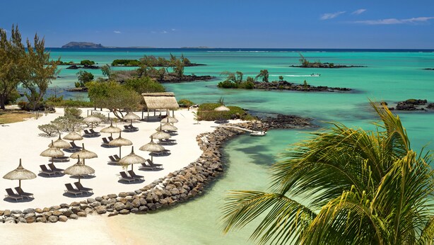 Un complexe hôtelier de bord de mer doté de chaises longues et de parasols, d’une côte rocheuse et d’eaux turquoise cristallines.
