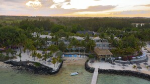 Un complexe hôtelier doté d’une plage, de palmiers et d’un espace piscine.
