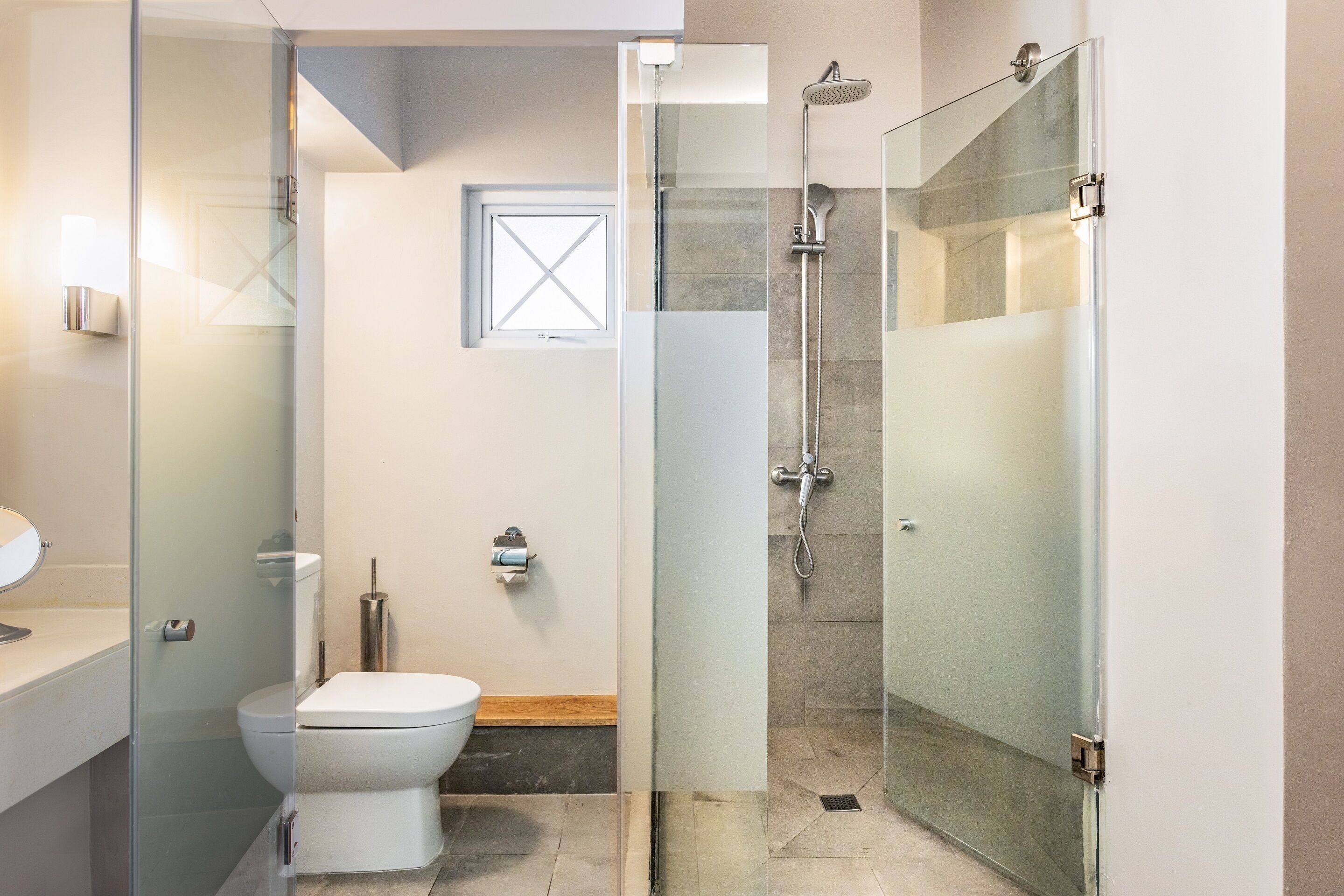 A modern bathroom with a glass-enclosed shower, a toilet, and a sink.