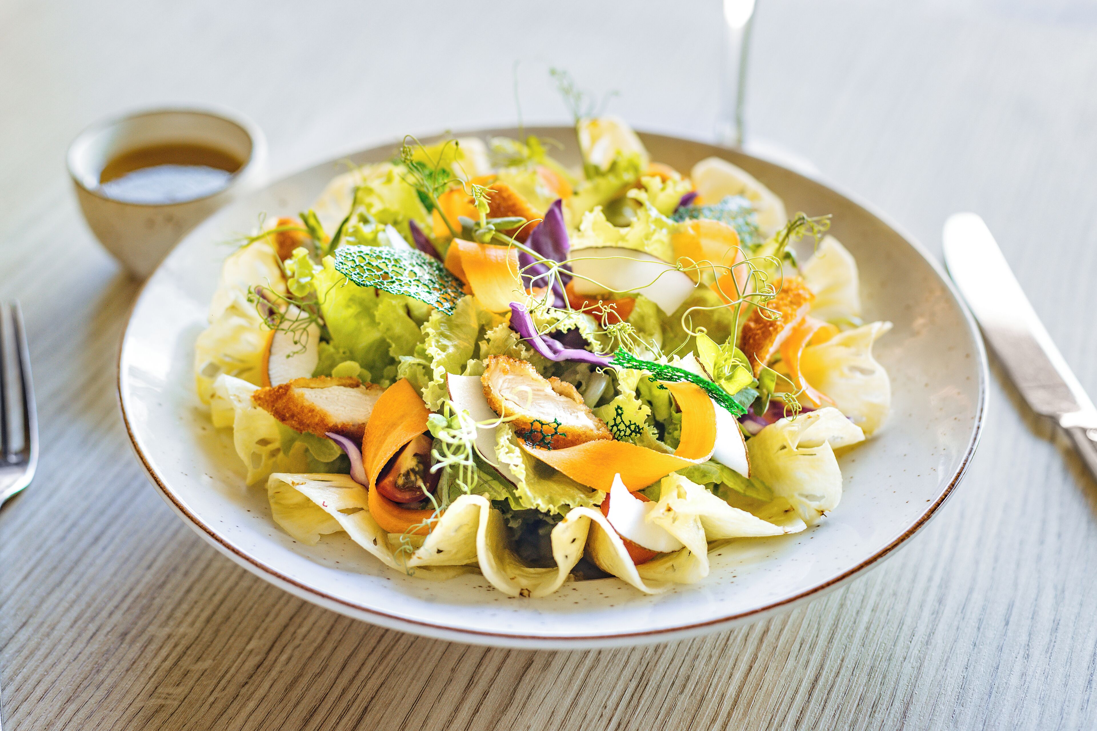 Une assiette de nourriture contenant divers légumes et un petit bol de sauce.