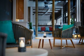 A modern indoor seating area with wicker furniture, a round table, and a lit candle. - Lagoon Attitude - Adults Only (Calodyne)