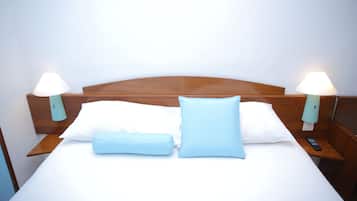 A neatly made bed with white and light blue pillows, wooden headboard, and bedside lamps.