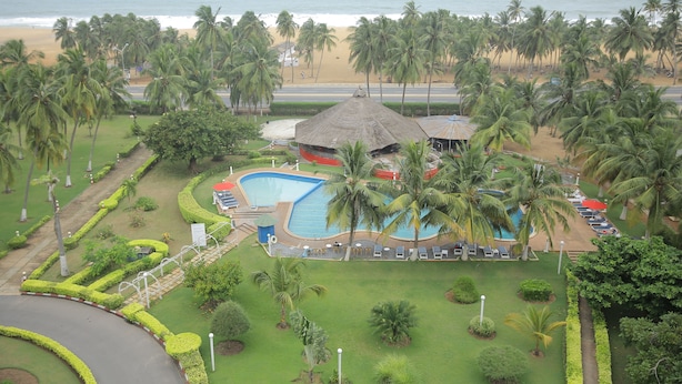 Un resort con piscina, palmeras y vista a la playa.