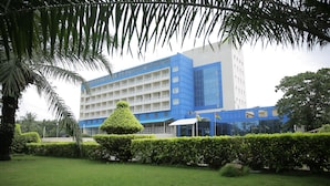 Un edificio moderno con fachada azul y blanca, rodeado de vegetación cuidada y un césped impecable.