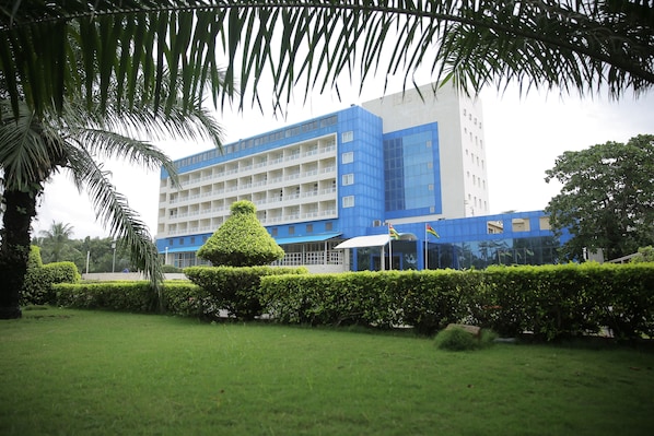 A modern building with a blue and white facade, surrounded by well-maintained greenery and a neatly trimmed lawn.
