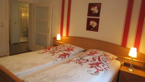 A double bed with floral bedding, bedside lamps, and a wooden headboard. - Ferienwohnungen Schmid (Lam)