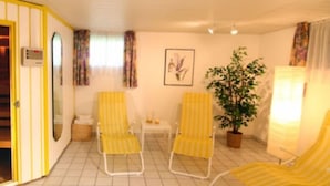A room with two yellow-striped chairs, a small table, a potted plant, and a framed picture on the wall. - Ferienwohnungen Schmid (Lam)