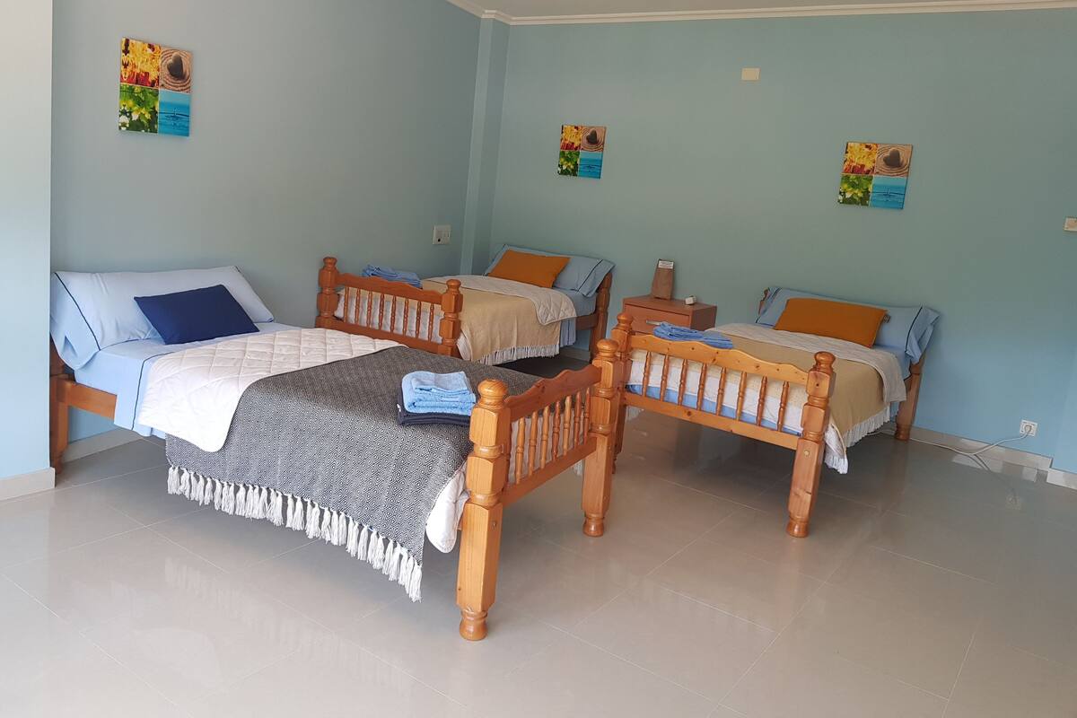 Una habitación con tres camas de madera, cada una con un edredón de diseño diferente.